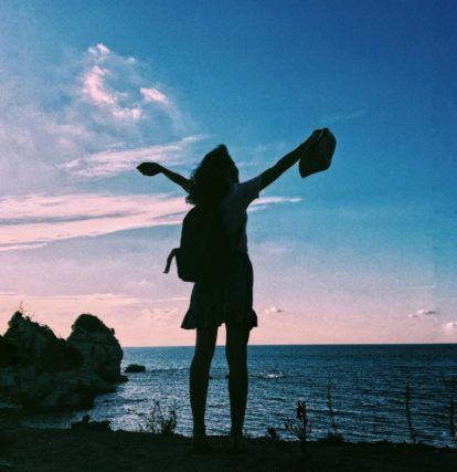 a woman standing on the edge of the ocean