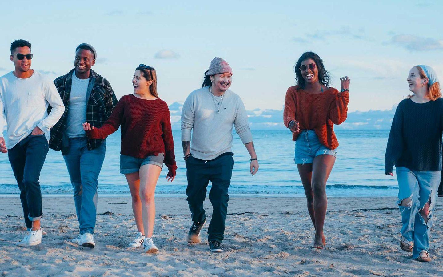 a group of people walking down a beach next to the ocean