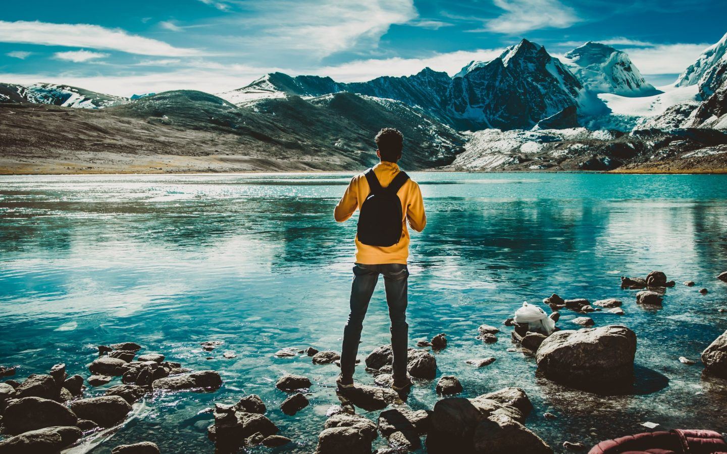 a man standing on a rocky shore next to a body of water