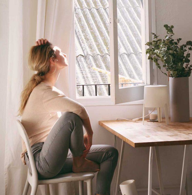 a woman sitting in a chair looking out a window