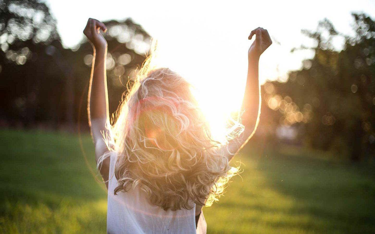 a woman standing in a field with her arms in the air