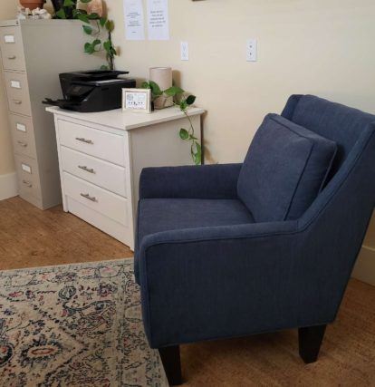 blue armchair next to a schest of drawers