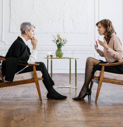 two women sitting in chairs across from each other